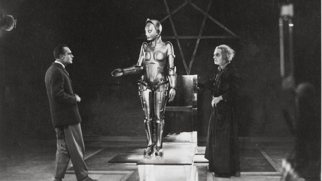 Fotograma de Metrópolis, con un robot al centro y dos personas.